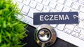 ECZEMA wrote on blue label tag with keyboard,stethoscope and green plant Royalty Free Stock Photo