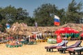 Ed CALANGUTE, GOA, INDIA JANUARY 3, 2019: Beautiful beach with beach plank bed and umbrellas, tanning Russian tourists, Russian