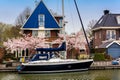 Traditional dutch house with yacht and blooming spring tree on the canal waterfront. Edam is a