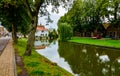 Edam, Netherlands, August 2019. One of the pretty canals of this city: the foliage of the trees is reflected on the water along Royalty Free Stock Photo