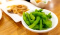 Edamame or green soybeans blanched in white bowl on wooden table at Japanese restaurant. Pods of green soy beans on blurred Royalty Free Stock Photo