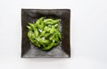 Edamame green soybeans in the bowl, fried green soybeans with salt in a black bowl on white background