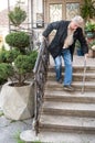 Ederly man with a cane descends down the stairs Royalty Free Stock Photo