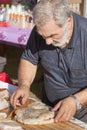 Ederly man preparing pizza with mortadella