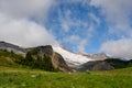 Edge of Mount Rainier Emerges from Cloud Behind Grassy Field Royalty Free Stock Photo
