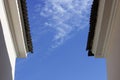 edge of the roof covered with slate Onduline on a background blue sky clouds. Royalty Free Stock Photo