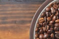 Edge of a saucer with coffee beans on a wooden board.