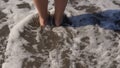 At the edge of the sea, woman`s feet/legs with the sea gently lapping them