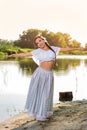 On the edge of the shore near the river stands a girl in a white dress. Royalty Free Stock Photo