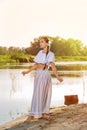 On the edge of the shore near the river stands a girl in a white dress. Royalty Free Stock Photo