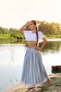 On the edge of the shore near the river stands a girl in a white dress. Royalty Free Stock Photo