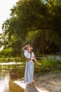 On the edge of the shore near the river stands a girl in a white dress. Royalty Free Stock Photo