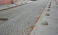 The edge of the sidewalk formed by concrete bollards in the shape of a hemisphere or a gray lens used to prevent cars from