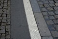 On the edge of the sidewalk is a white safety line with bumps protrusions that warn blind people that they are approaching the tra Royalty Free Stock Photo