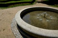 Edge of a stone sandstone circular fountain in the park. built of sandstone filled with water. lined with a light threshing gravel Royalty Free Stock Photo