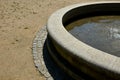 Edge of a stone sandstone circular fountain in the park. built of sandstone filled with water. lined with a light threshing gravel Royalty Free Stock Photo