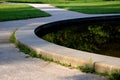 Edge of a stone sandstone circular fountain in the park. built of sandstone filled with water. lined with a light threshing gravel Royalty Free Stock Photo