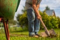 The edge of the wheelbarrow in the garden. In the background, a farmer is digging the ground with a shovel.