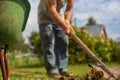 The edge of the wheelbarrow in the garden. In the background, a farmer is digging the ground with a shovel