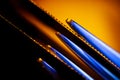 Edges of two illuminated serrated knives and prongs of a fork macro shot suitable as a background