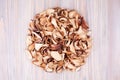 Edible dried mushrooms pile light wooden background closeup top view, dry boletus edulis heap wood backdrop, brown cap boletus