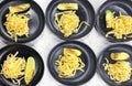 Edible pattern from black plates with spaghetti. On the plates are pasta and grilled zucchini