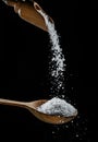 Edible salt crystals falling down into the wooden spoon at black background Royalty Free Stock Photo