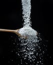 Edible salt crystals falling down into the wooden spoon at black background Royalty Free Stock Photo