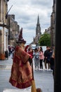 A street performer on the Royal Mile in Edinburgh dressed as a witch and holding a broom appears to float in the air