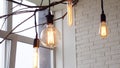 Edison hanging lamps, illuminated. Media. Vintage light bulbs hanging on interior branches of window on background of Royalty Free Stock Photo