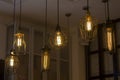 Edison`s antique lamps of various shapes and sizes in lampshades glow in the dark under the ceiling