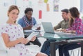 Editor holding tablet and smiling as team works behind her Royalty Free Stock Photo