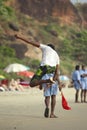 Kerala, India - 01.02.2011: A young Indian man jumps to catch a frisbee on the beach with coastguards and beachgoers in the