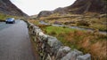 Editorial, Road through Rugged Mountain pass with dry stone wall in foreground, stream behind.