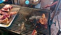 Editorial. Street food vendor grilling a piece of meat for making pork and rice or bai sach chrouk