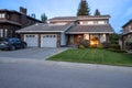 Two store dwelling house with double garage and sunset reflection in window and fresh moved front lawn