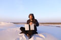 Educated Arab student uses laptop and works sitting on sand amid