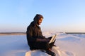 Educated Arab student uses laptop and works sitting on sand amid