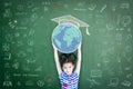 Educated school child girl lifting world globe doodle on chalkboard for children`s education international children day