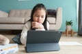 Education. Asian girl is learning with online tutor via the internet on tablet digital in morning. Asia children doing homework wi Royalty Free Stock Photo