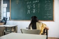 Back view of school girl on lesson in classroom write hardworking on blackboard Royalty Free Stock Photo