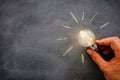 Education and business concept image. Creative idea and innovation. Man holding a light bulbs as metaphor over blackboard Royalty Free Stock Photo