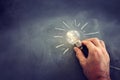 Education and business concept image. Creative idea and innovation. Man holding a light bulbs as metaphor over blackboard Royalty Free Stock Photo
