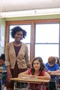 Education, classroom and portrait of black woman with girl writing exam or help with test in notebook at Montessori