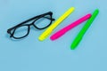 Education concept. Glasses and three markers on a blue background with copy space Royalty Free Stock Photo