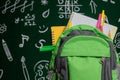 Education concept - green backpack, notebooks and school supplies on the background of the blackboard Royalty Free Stock Photo