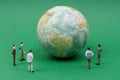 On the green surface is a planet around which there are figures of people. Royalty Free Stock Photo