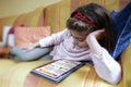 education concept. Little girl lying on the sofa at home studying home work on the tablet