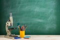 Education concept - microscope on the desk in the auditorium, blackboard background