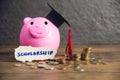 Education concept with money coin and graduation cap on pink piggy bank saving money for scholarships